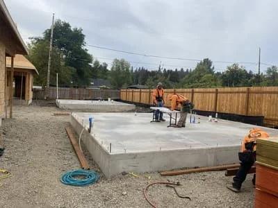 Concrete foundation pad with wooden fence and gravel base for deck construction