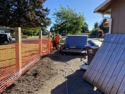 Vertical panel siding installation on home exterior with blue finish and protective fencing