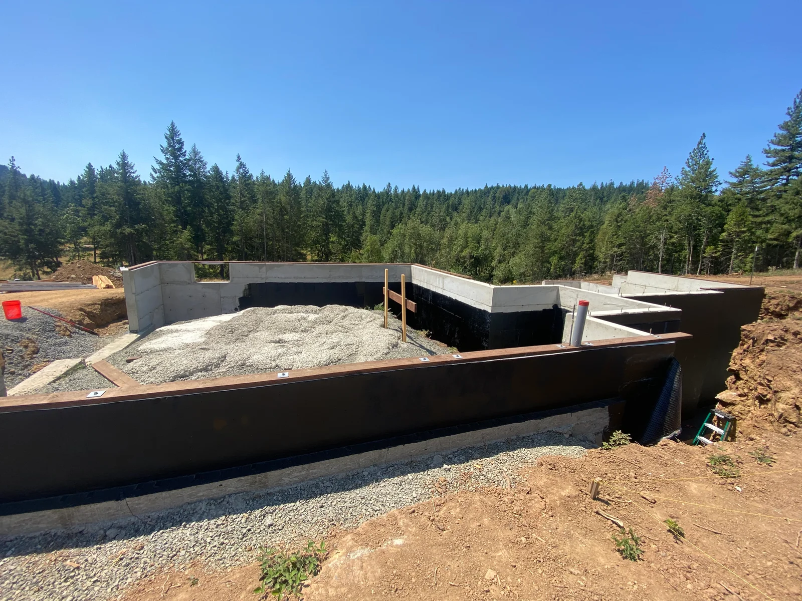 Concrete foundation walls with reinforced framing, gravel base, and drainage preparation