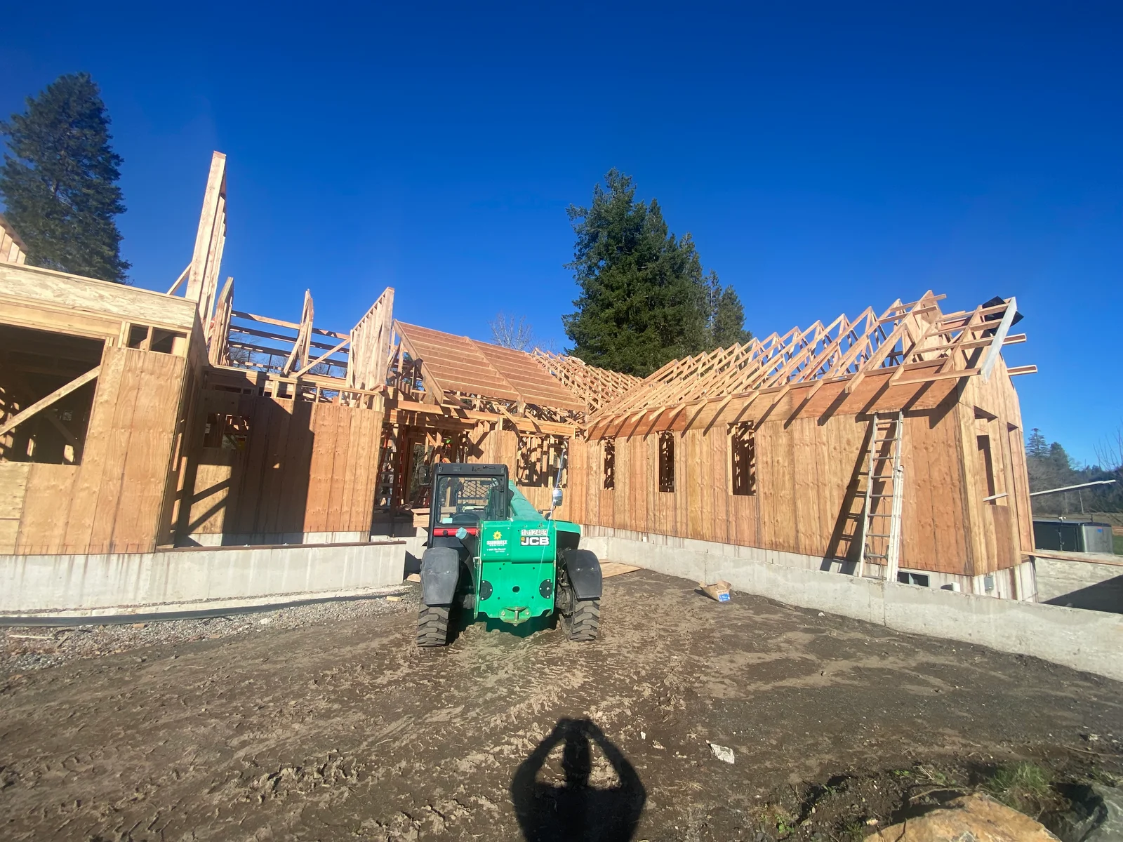 Wood-framed residential home under construction with exposed trusses and concrete foundation