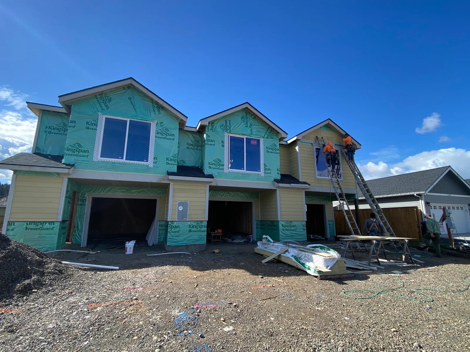 Two-story home with fiber cement siding and weather barrier wrap during installation phase