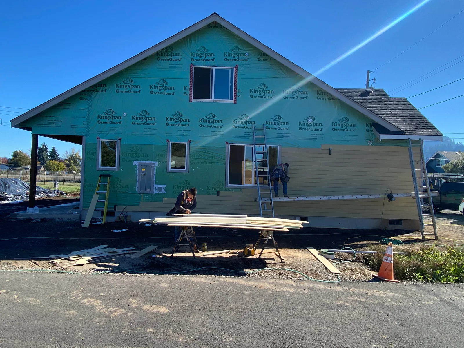 House wrap and fiber cement siding installation in progress on residential home exterior