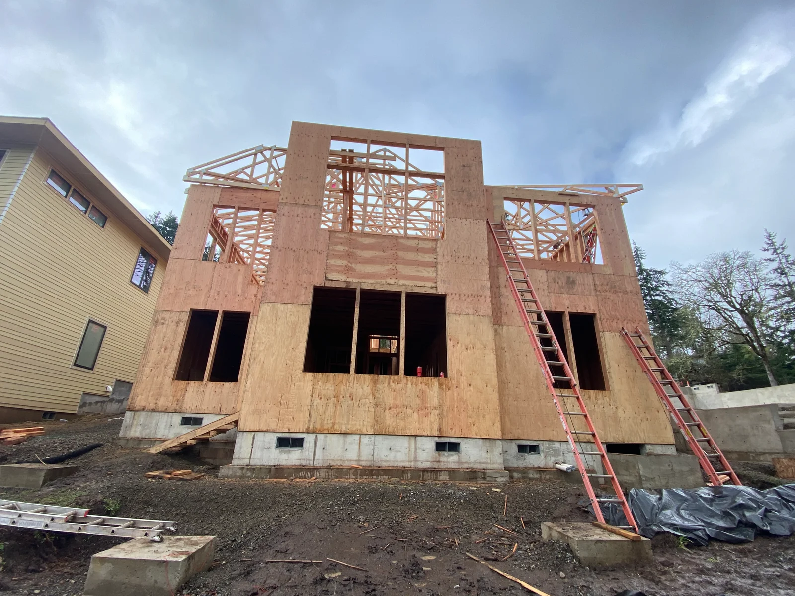 Two-story wood frame house with OSB sheathing, roof trusses, and concrete foundation during construction