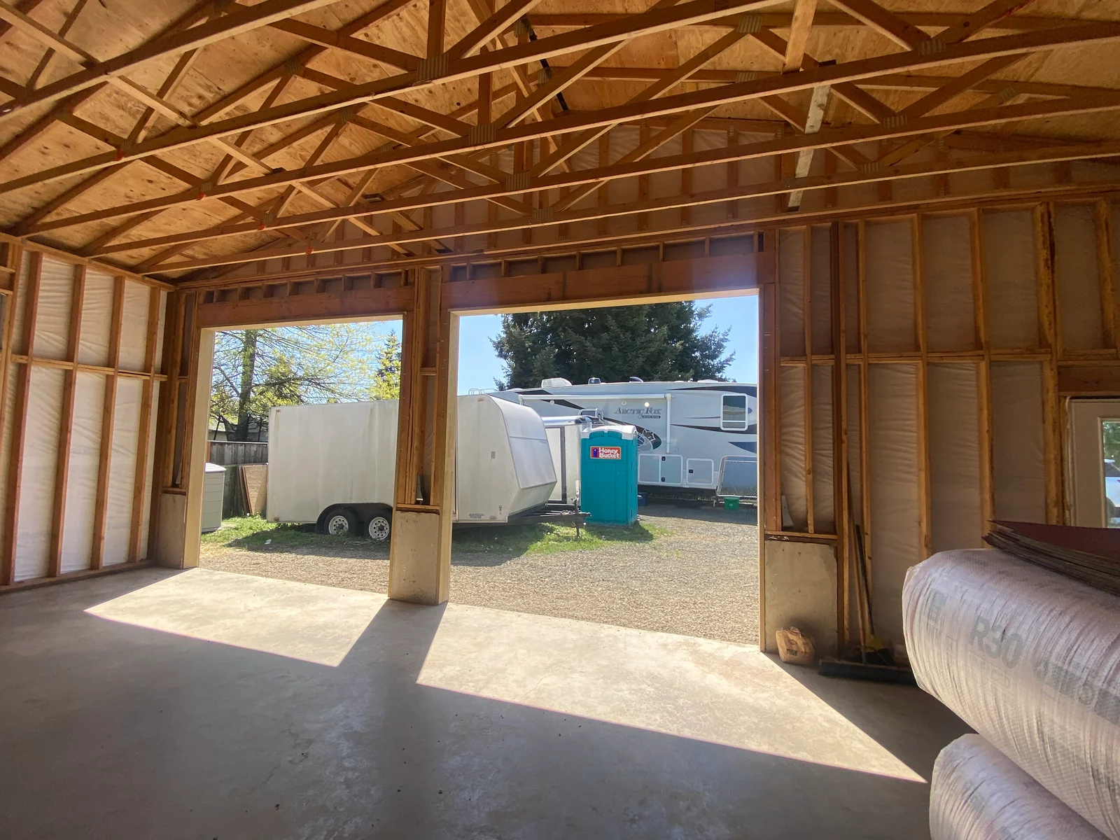 Interior of RV storage building with wooden truss framing and concrete floor