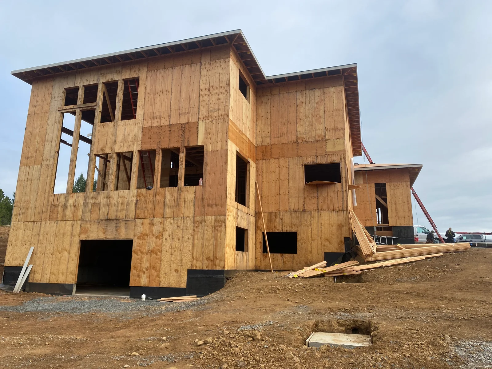 Multi-story home framing with OSB sheathing, window openings, and wooden deck structure