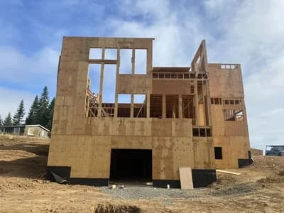 Two-story home framing with OSB sheathing, window openings, and concrete foundation