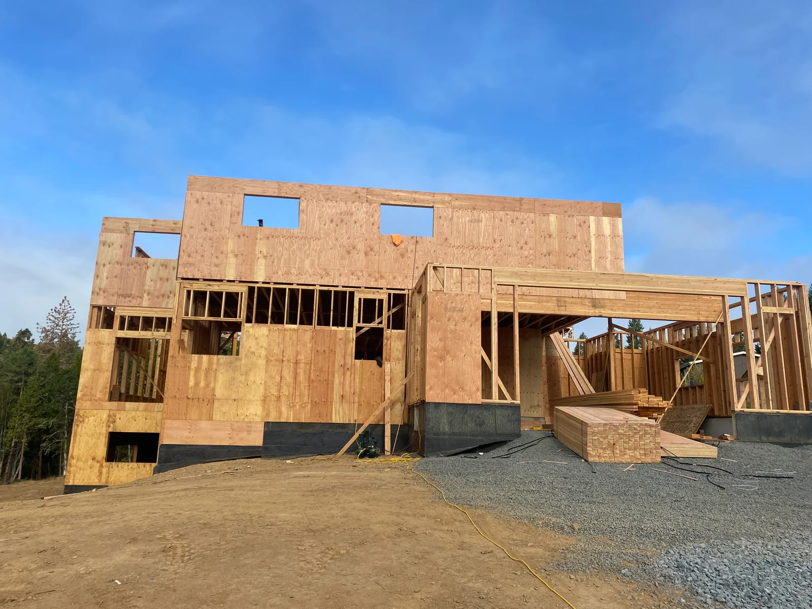 Two-story home framing with OSB sheathing, window openings, and elevated foundation on gravel base