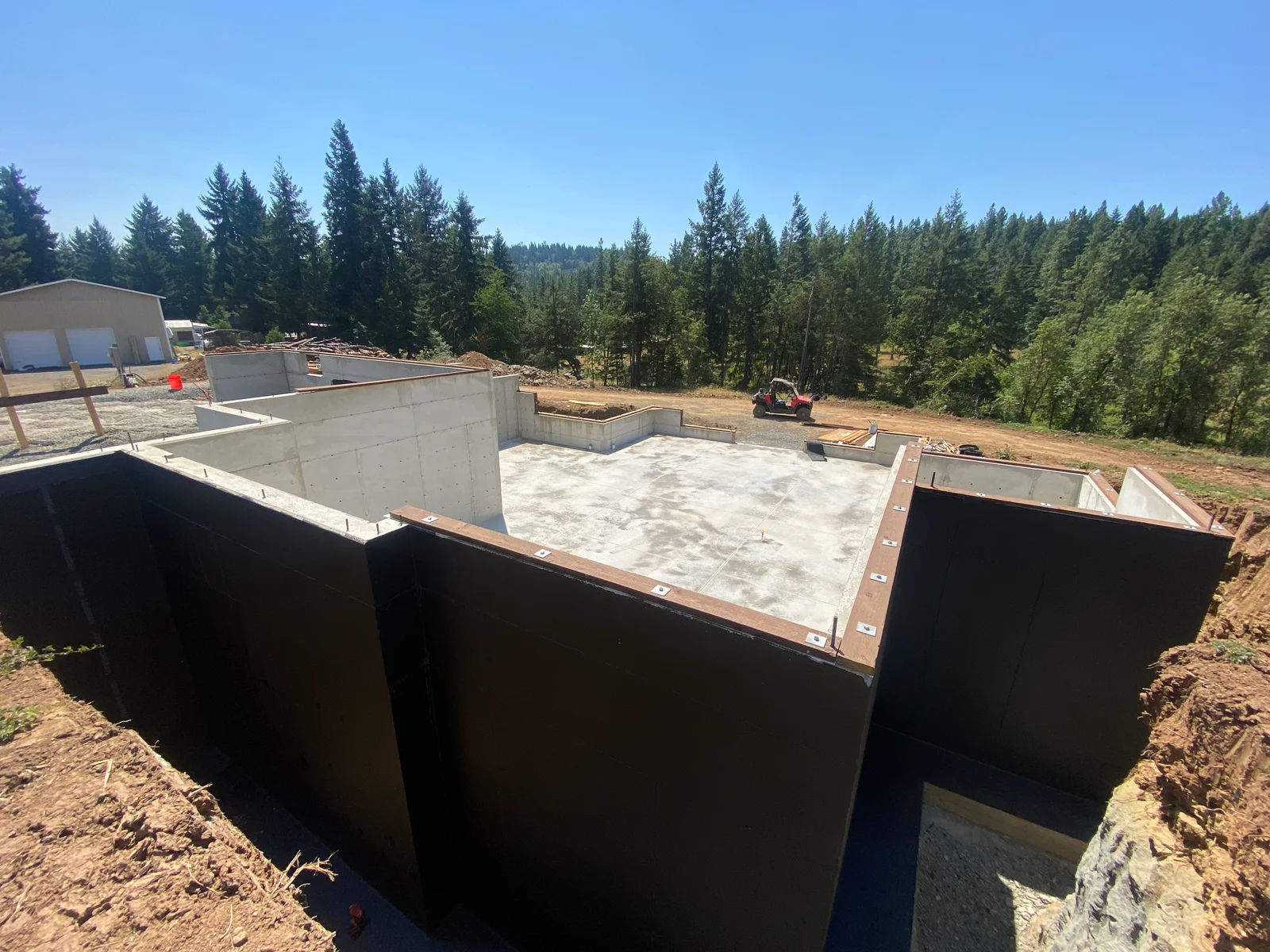 Concrete foundation walls with black waterproofing membrane and steel reinforcement during construction
