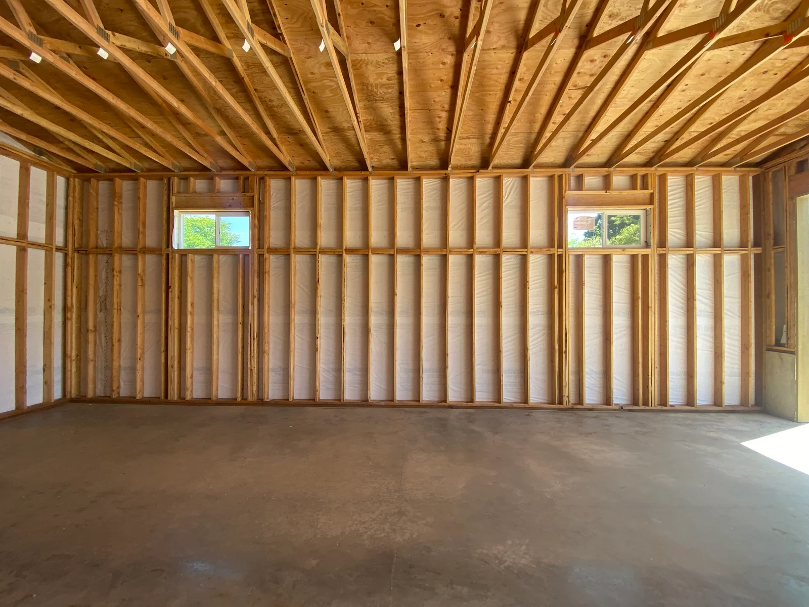 Interior framed walls with fiberglass insulation, wooden studs, and installed windows