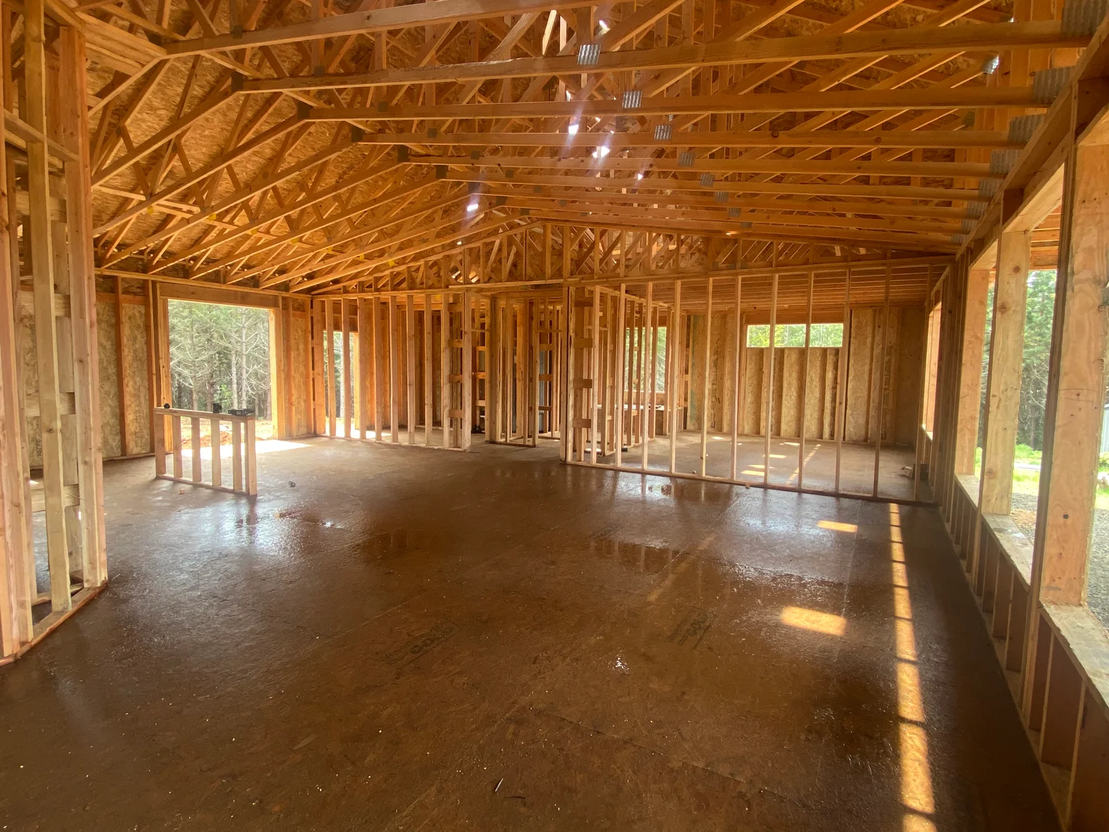 Interior framing with wood trusses, studs, concrete floor, and window openings
