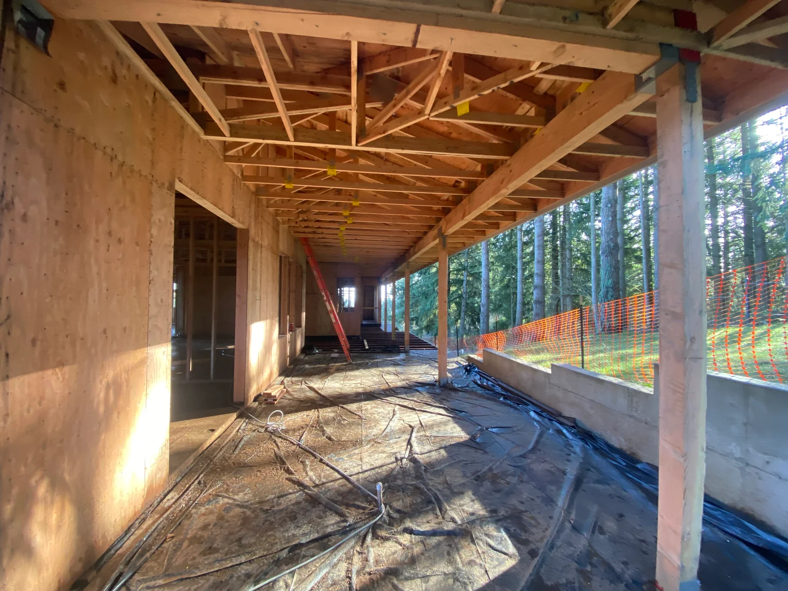 Wooden roof framing and beams in residential construction with concrete walls and safety fencing