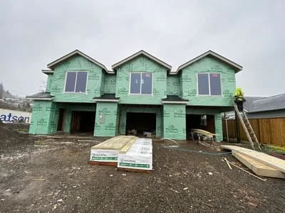 Green house wrap and weather barrier on three-unit residential siding project with window openings