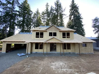 Two-story home with tan fiber cement board siding and attached garage during installation phase