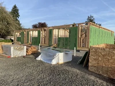 Green and tan corrugated metal siding panels installed on residential framing structure