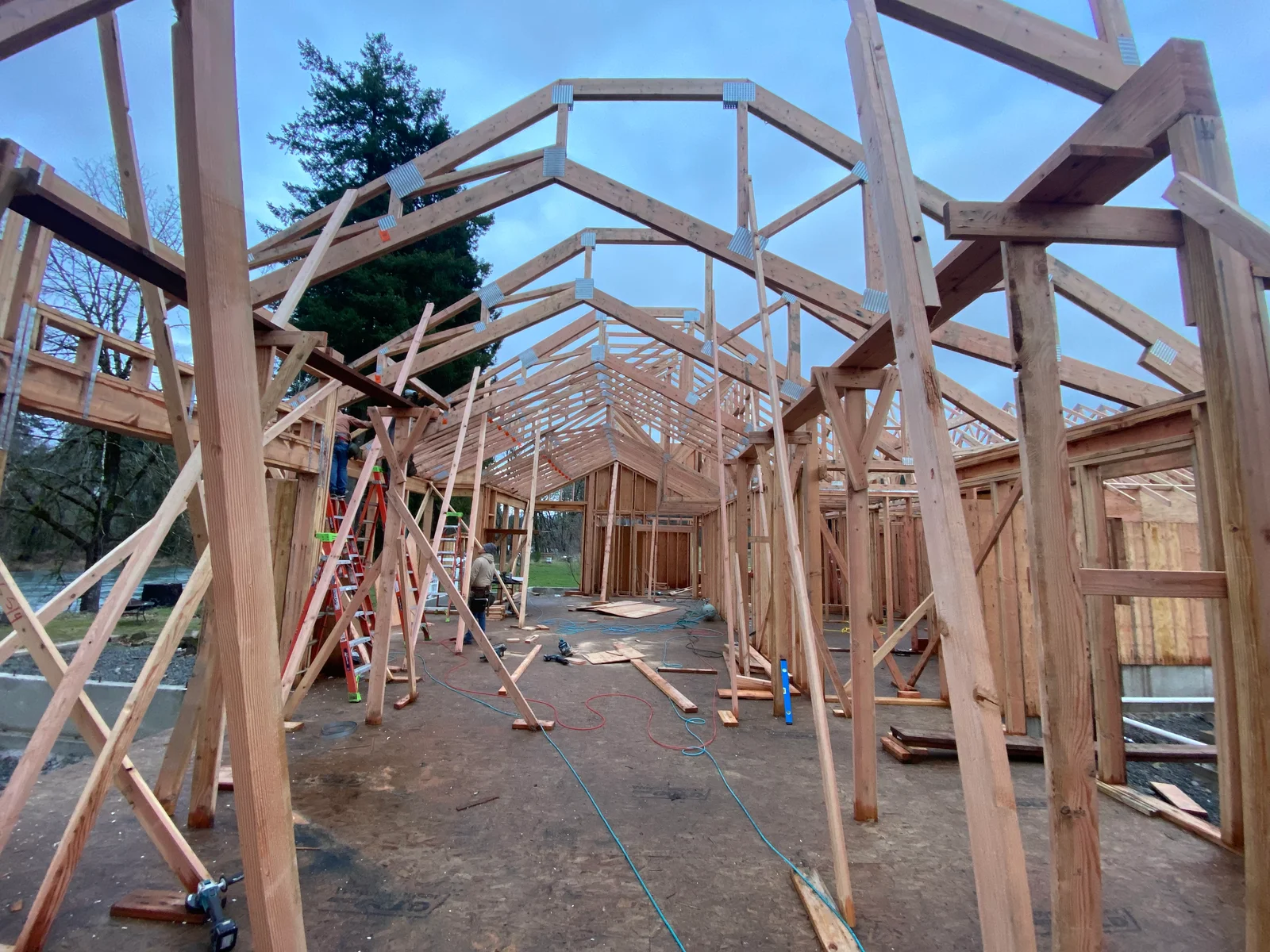 Timber frame construction with wooden posts, beams, and roof trusses during framing phase