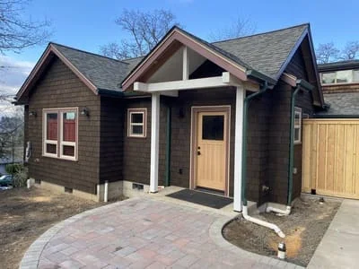Dark fiber cement siding with white trim and gable details on cottage-style home