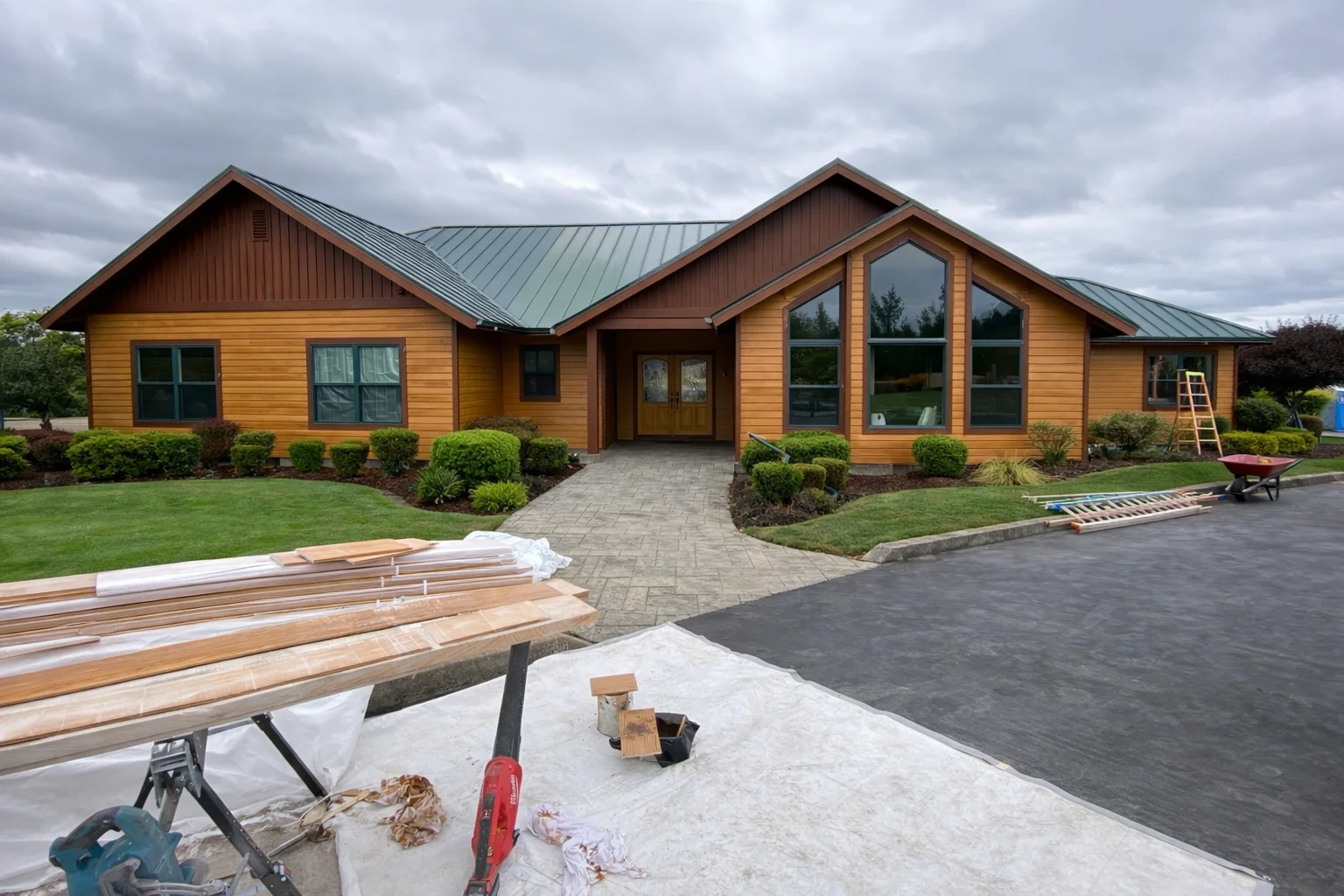 Golden fiber cement siding with dark trim on modern ranch home with metal roof and large windows